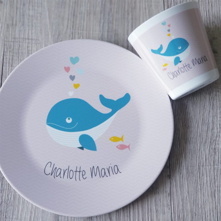 Taufgeschirr Wal Ein Teller und ein Becher mit einem blauen Wal auf rosa Hintergrund und dem Namen "Charlotte Mana".